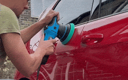 Man using a dual action polisher to polish a red car