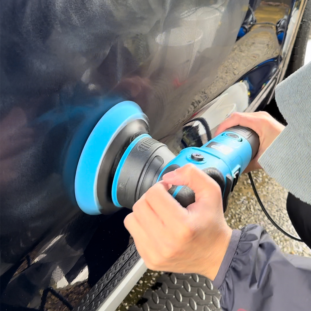 Using a dual-action polisher to polish the paint on a Blue Audi Q3