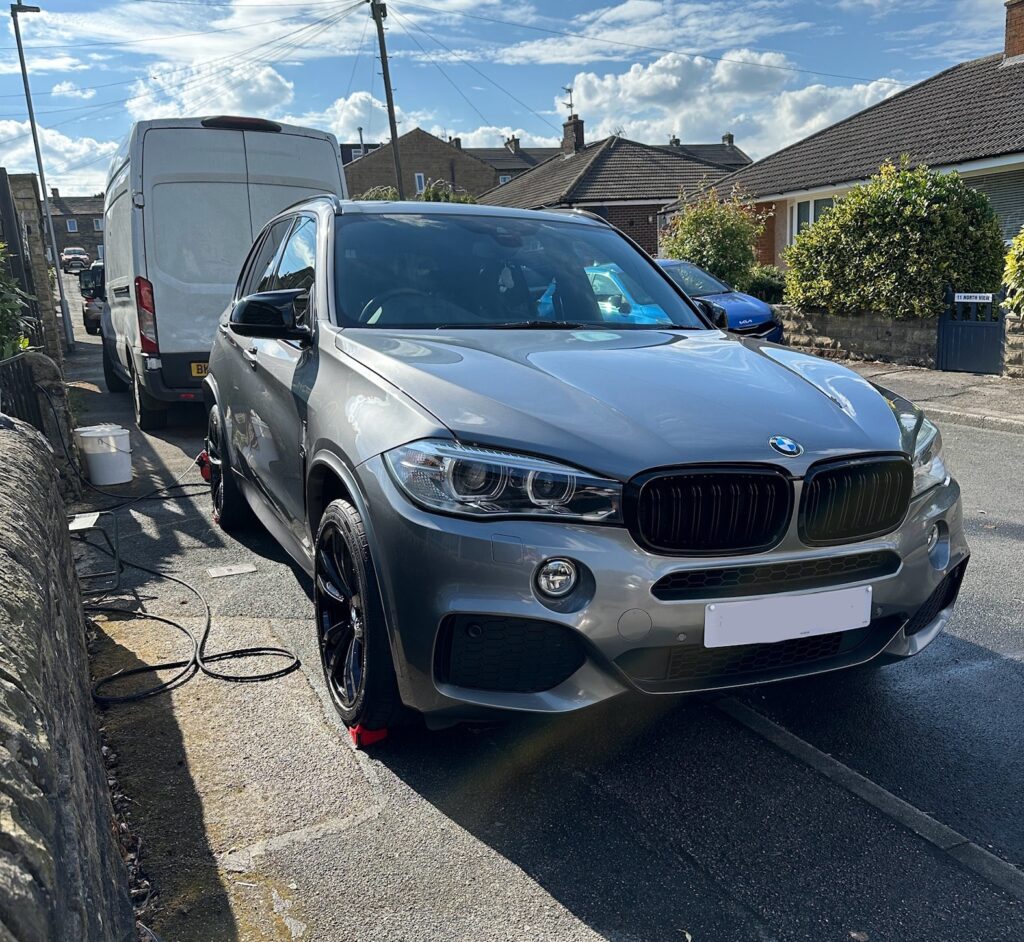 BMW X5 next to a drive being cleaned