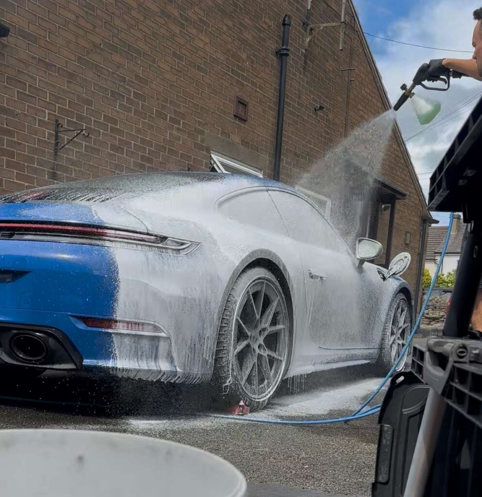 Blue Porsche being detailed using snow foam cannon
