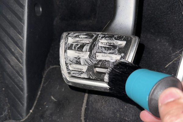 Brake pedal being cleaned using brush and soap